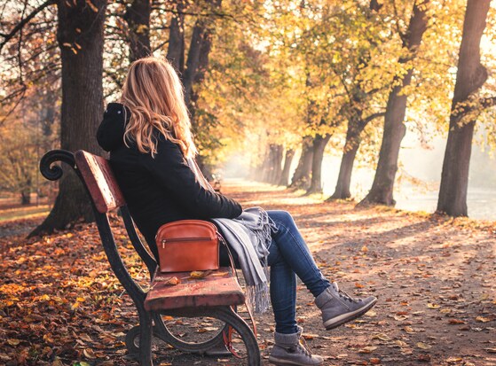 A woman on an autumn park bench, representing the journey of different types of trauma therapy and how to choose the right approach for healing, recovery, and emotional stability.